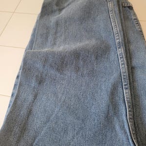 Puede incluir: Vaqueros de mezclilla azul claro, doblados. Los vaqueros tienen un dise&ntilde;o cl&aacute;sico de cinco bolsillos, cremallera y corte recto. La tela muestra una sutil decoloraci&oacute;n y desgaste.