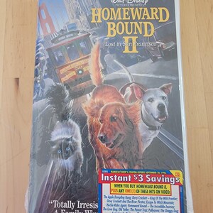May include: A VHS tape case for the movie Homeward Bound II: Lost in San Francisco. The case features a colorful illustration of a cat, two dogs, and a cable car in front of the Golden Gate Bridge. The text "Instant $3 Savings" is on the bottom right corner of the case.