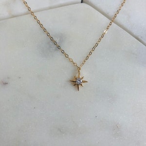 May include: A gold chain necklace with a small, sparkling star pendant.