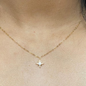 May include: A gold chain necklace with a small star pendant featuring a clear crystal in the center.