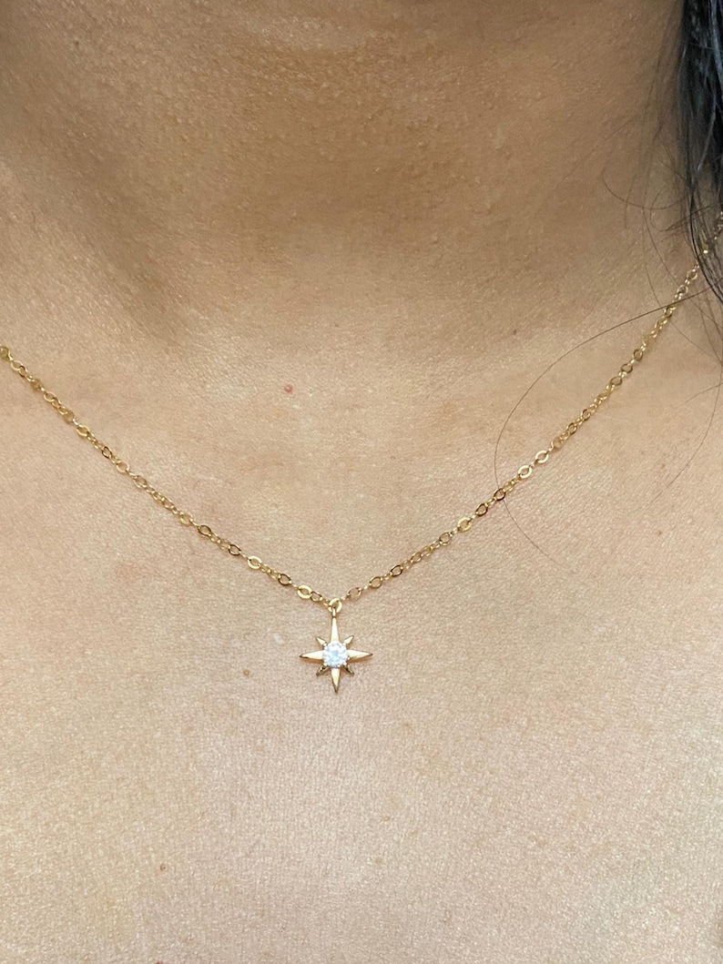 May include: A gold chain necklace with a small star pendant featuring a clear crystal in the center.