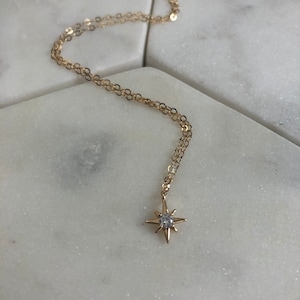 May include: A gold chain necklace with a small, sparkling star pendant.