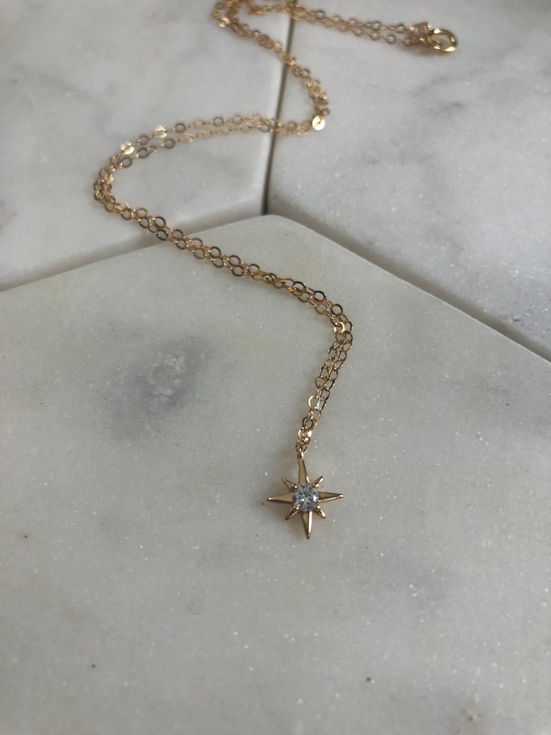 May include: A gold chain necklace with a small, sparkling star pendant.