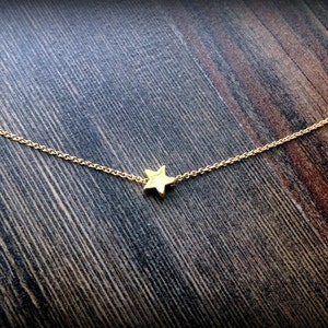 May include: A delicate gold chain necklace with a small, simple star pendant.