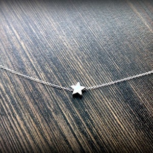 May include: A delicate silver chain necklace with a small, star-shaped pendant.