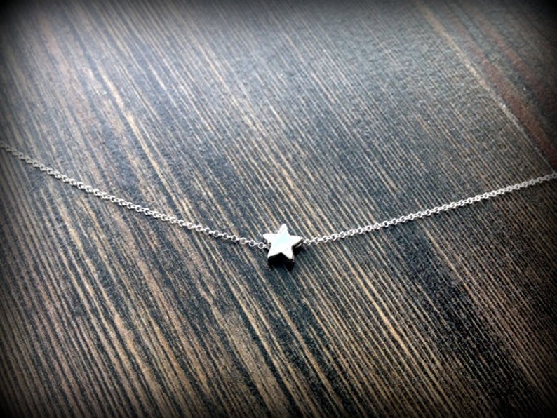 May include: A delicate silver chain necklace with a small, star-shaped pendant.