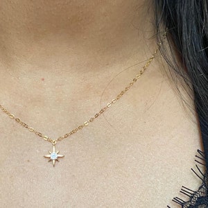 May include: A gold chain necklace with a small star pendant featuring a clear crystal in the center.
