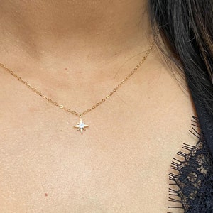 May include: A gold chain necklace with a small, star-shaped pendant featuring a clear stone in the center.