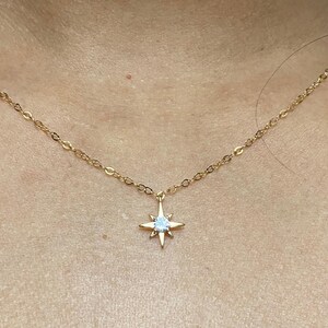 May include: A gold chain necklace with a star pendant featuring a clear crystal in the center.