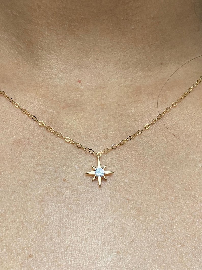May include: A gold chain necklace with a star pendant featuring a clear crystal in the center.