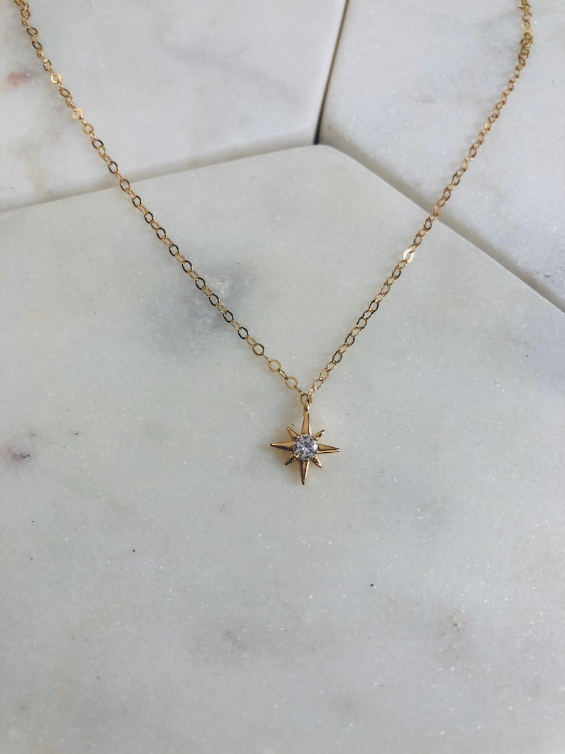 May include: A gold chain necklace with a small, sparkling star pendant.
