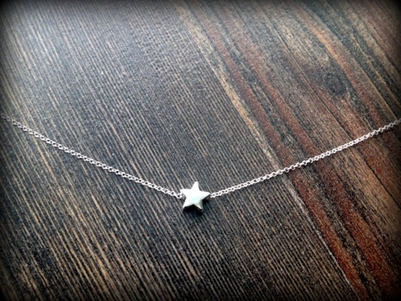 May include: A delicate silver chain necklace with a small, five-pointed star pendant.