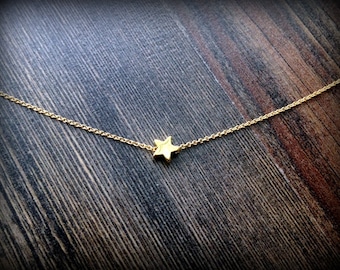 Puede incluir: Un delicado collar de cadena dorada con un pequeño colgante de estrella simple.
