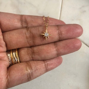 May include: A gold chain necklace with a small, clear crystal star pendant.