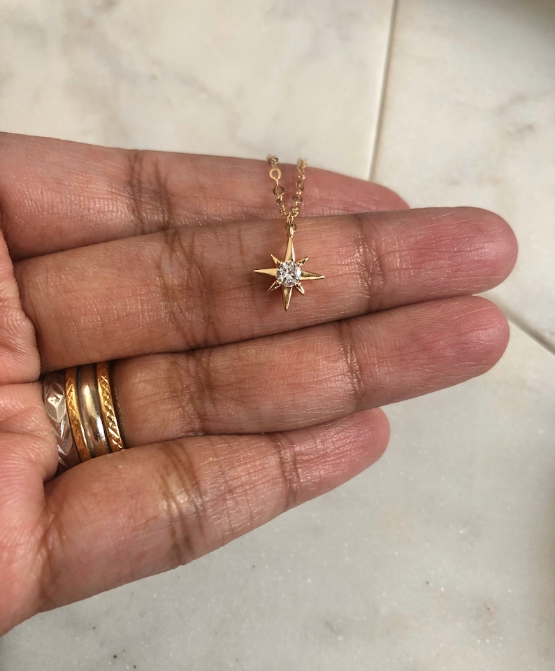 May include: A gold chain necklace with a small, clear crystal star pendant.