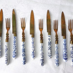 May include: Set of ten gold-tone forks and knives with blue and white porcelain handles. The handles feature a floral design.