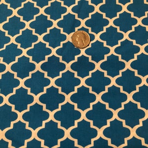 May include: Teal fabric with a repeating quatrefoil pattern in off-white. A U.S. quarter coin is placed on the fabric for scale. The fabric has a textured appearance and is likely cotton or a similar material.