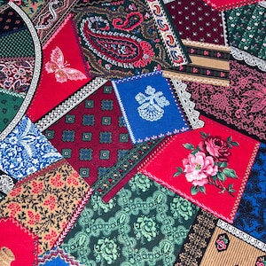 May include: A patchwork textile featuring a variety of patterned fabric squares in red, blue, green, and brown. The patterns include floral designs, paisley, and geometric shapes. Some squares have lace trim, and a butterfly is visible.