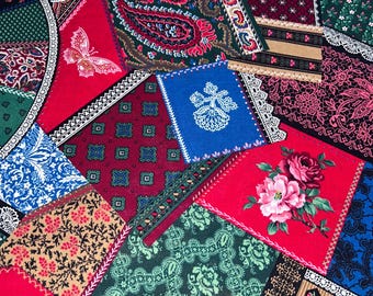 May include: A patchwork textile featuring a variety of patterned fabric squares in red, blue, green, and brown. The patterns include floral designs, paisley, and geometric shapes. Some squares have lace trim, and a butterfly is visible.