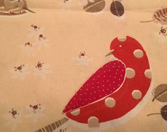 May include: A close-up of a fabric with a repeating pattern of stylized birds, leaves, and floral elements. The birds are red with white polka dots and brown wings. The background is a light beige color.
