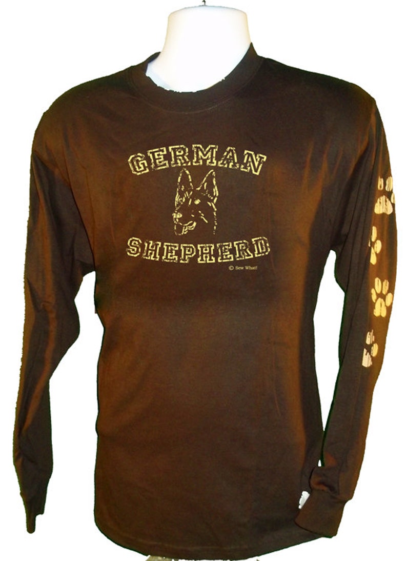 May include: Brown long-sleeve t-shirt with a gold graphic of a German Shepherd dog and the text "GERMAN SHEPHERD" with paw prints on the sleeves.