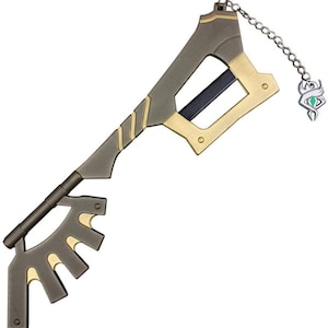May include: A gold and black metal keyblade with a chain and a green gem charm. The keyblade has a sharp blade and a decorative handle.