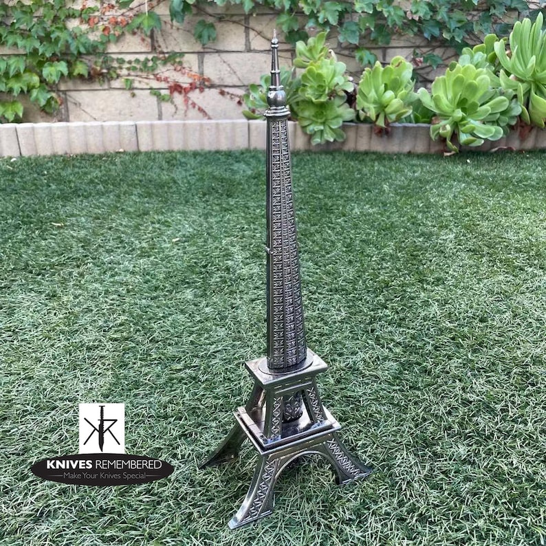 May include: A silver Eiffel Tower-shaped knife holder with the text "Knives Remembered - Make Your Knives Special" on the base.