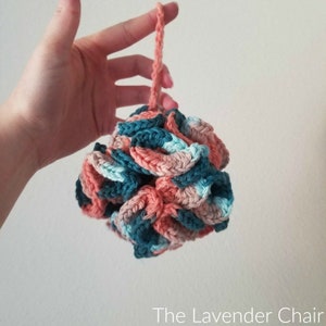 Può includere: Un pouf da bagno all'uncinetto in tonalità turchese, rosa e bianco. Il pouf è rotondo e ha un lungo anello all'uncinetto per appenderlo.