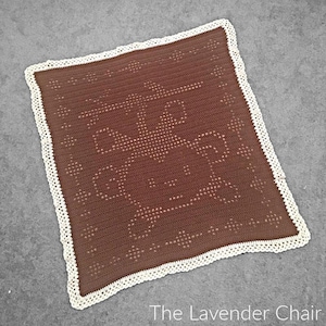 Könnte beinhalten: Eine braune gehäkelte Babydecke mit einem weißen gehäkelten Rand. Die Decke hat ein sich wiederholendes Muster aus kleinen Kreisen.