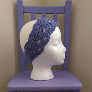 May include: A purple crocheted headband on a white mannequin head. The headband has a delicate, lacy design.