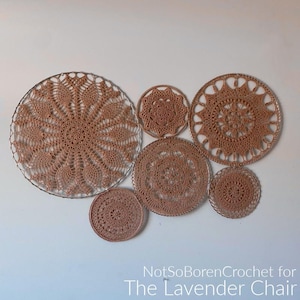 May include: A set of six crocheted doilies in a light peach colour, arranged on a white wall. The doilies are different sizes and have intricate patterns. The text "NotSoBorenCrochet for The Lavender Chair" is written below the doilies.
