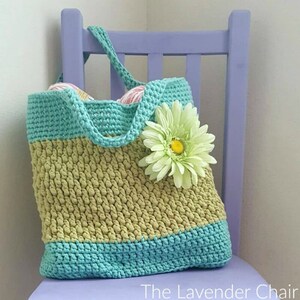 May include: A crocheted tote bag with a green and blue striped design. The bag has a single strap and is decorated with a green flower.