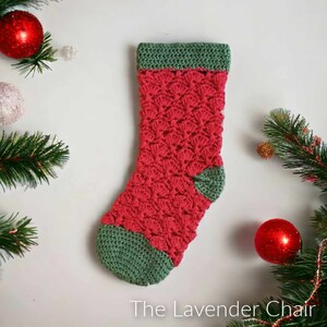 May include: A crocheted Christmas stocking in red and green. The stocking features a textured pattern and has a green cuff and toe.