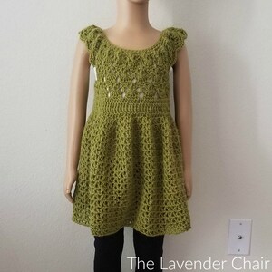 May include: A green crochet dress with a scalloped neckline and short sleeves. The dress has a fitted bodice and a flared skirt.