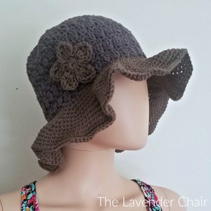 May include: A brown crocheted sun hat with a flower detail. The hat has a wide brim and a ruffled edge.