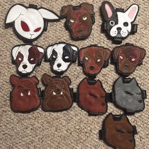 Puede incluir: Una colección de 12 parches de cuero con diferentes caras de animales, incluyendo un conejo, un bulldog, un bulldog francés y un pitbull. Los parches son marrones, negros, blancos y grises.