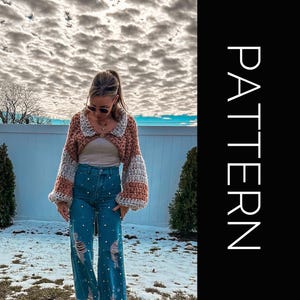 May include: A cropped, pink and white striped crochet cardigan with puffed sleeves. The cardigan is worn over a white tank top and blue jeans.
