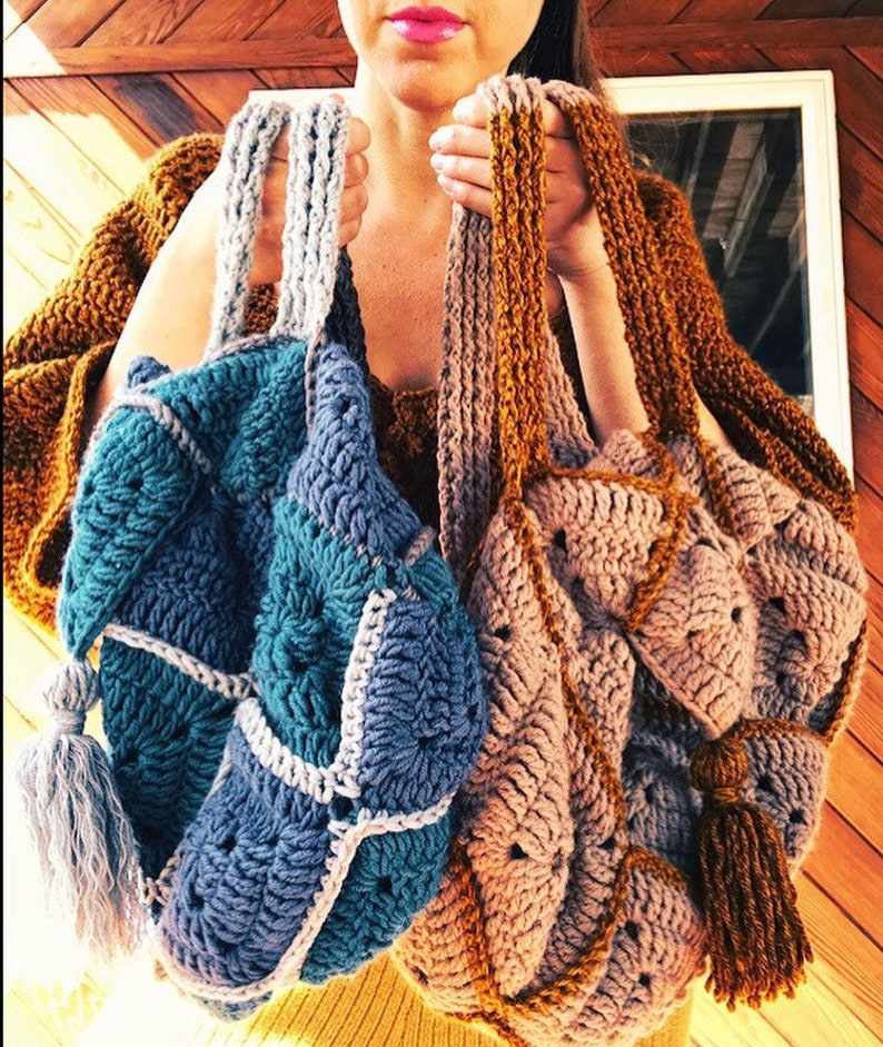 May include: Two crocheted tote bags with tassels. One bag is teal, blue, and white. The other bag is brown, beige, and gold.