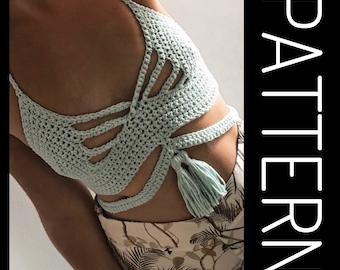 May include: A light green crochet top with a criss-cross design and a tassel. The top is made with a delicate stitch and has a relaxed fit.