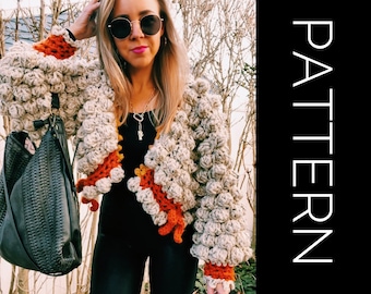 May include: A beige crochet cardigan with orange and yellow accents. The cardigan has a textured, puffy design and is cropped.