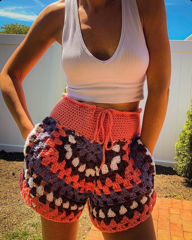 Puede incluir: Un par de pantalones cortos de crochet en tonos rosa, morado, blanco y marr&oacute;n. Los pantalones cortos tienen cintura alta y un lazo en la parte delantera.