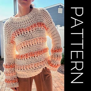 May include: A crocheted sweater with a white and orange striped pattern. The sweater has a loose fit and long sleeves with a bell shape at the cuffs.