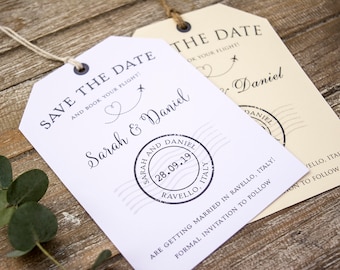 Può includere: Etichette per bagagli bianche e crema con testo nero. Il testo recita "Save the Date and book your flight!" con un cuore e un aereo. L'etichetta include anche i nomi "Sarah & Daniel" e la data "28.09.19" con la località "Ravello, Italia".