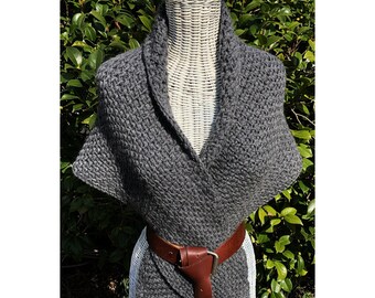 Puede incluir: Un chal de punto gris con un cinturón de cuero marrón. El chal está drapeado sobre un maniquí blanco y tiene un cuello en V.