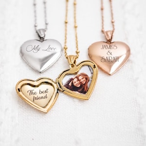 Könnte beinhalten: Drei herzförmige Medaillon-Halsketten in Silber-, Gold- und Roségoldtönen. Ein goldenes Medaillon ist geöffnet und zeigt ein Foto von zwei Personen sowie den eingravierten Text The best friend. Das silberne Medaillon trägt die Gravur My Love, das roségoldene JAMES & SARAH.
