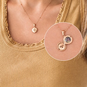 May include: A rose gold locket necklace on a delicate chain. The circular locket features a floral engraving on the front. When opened, the interior reveals a small circular photograph and the engraved text "Mum" accompanied by a tiny heart symbol.
