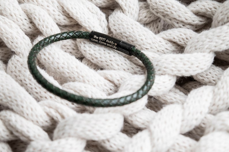 A dark green woven leather bracelet for men, with a black clasp engraved on the inside with a personalised message.