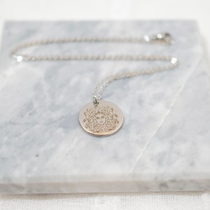 Silver Medusa pendant necklace on marble background