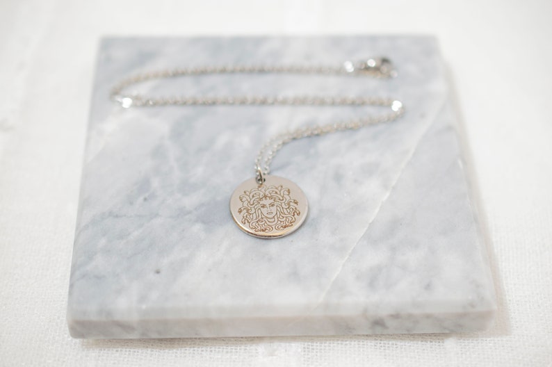 Silver Medusa pendant necklace on marble background