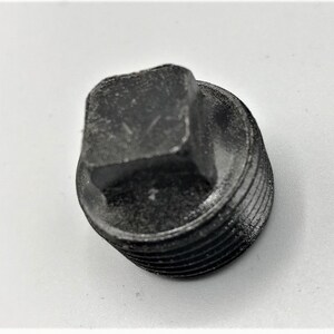May include: A black metal pipe plug with a square head and a threaded body.